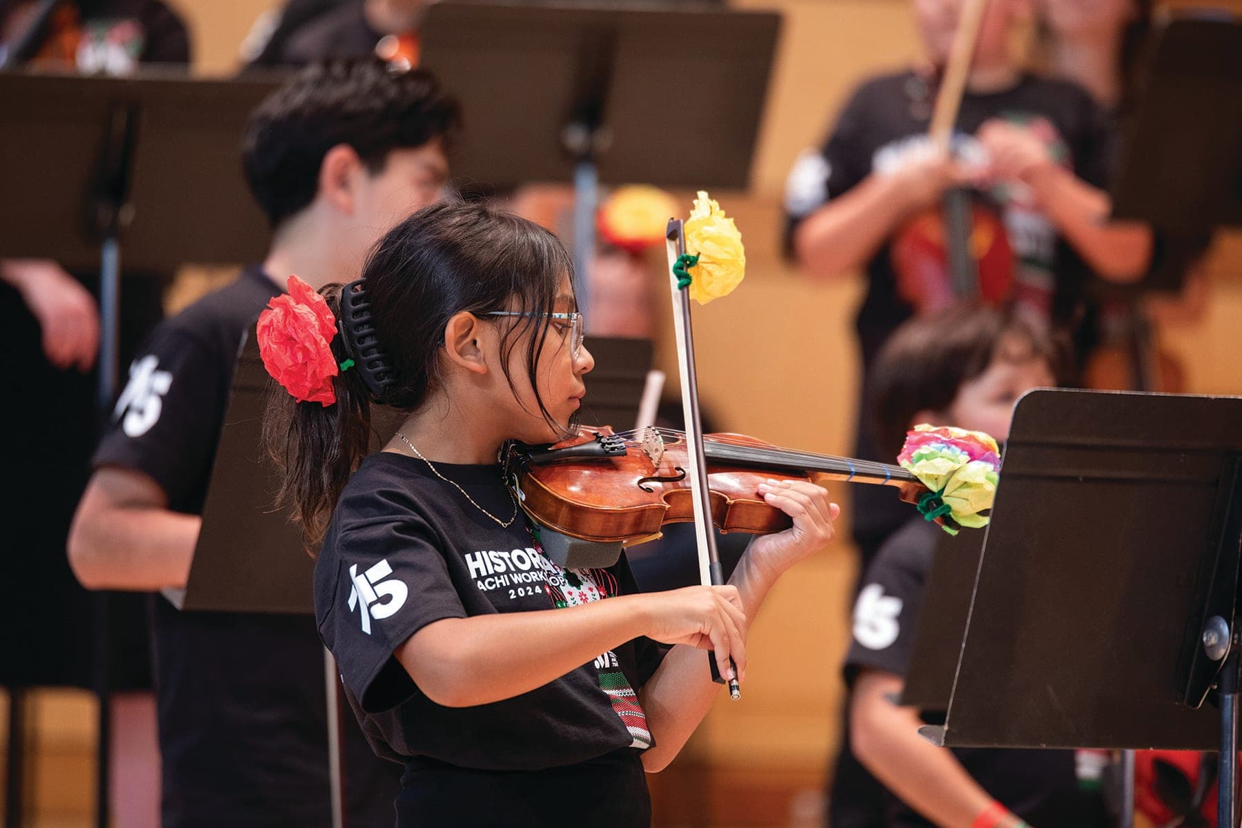 A young girl playing a violin in a orchestra