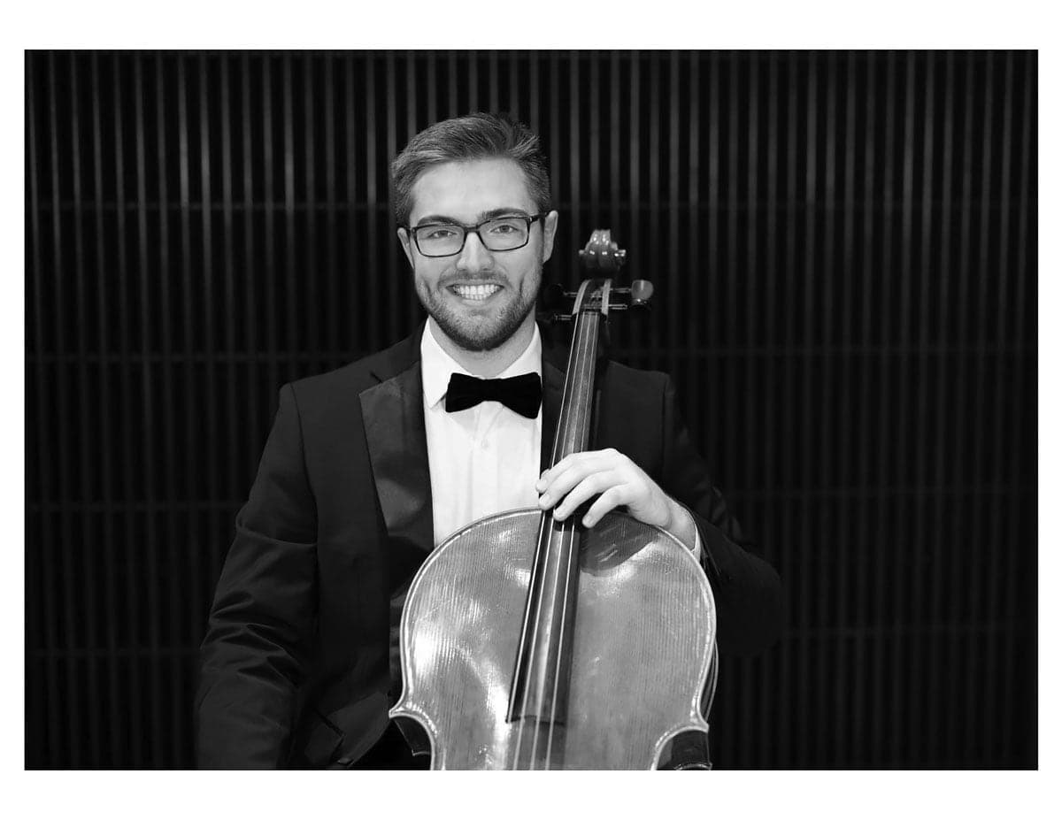 A man in a tuxedo holding a cello