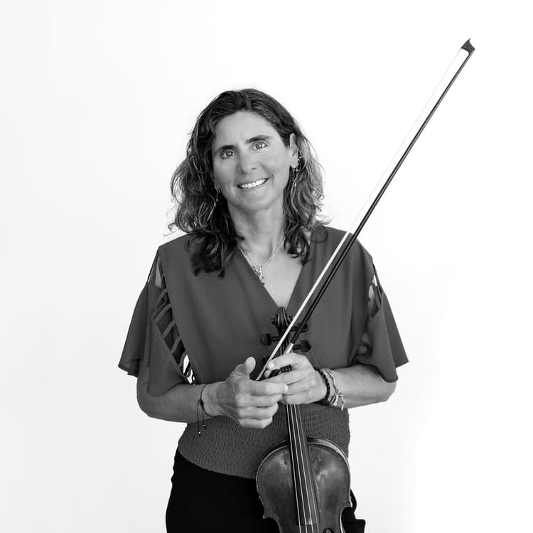 A woman is holding a violin and smiling