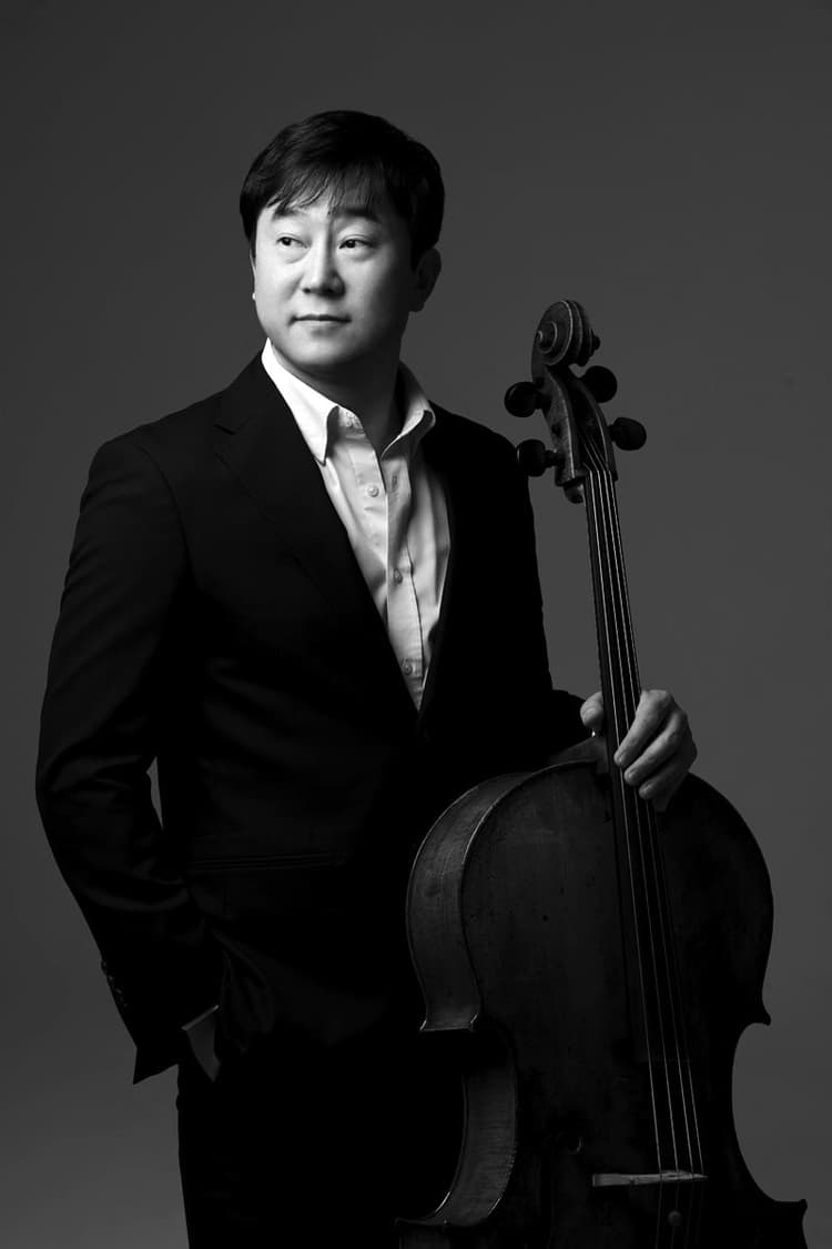 A man in a suit holding a cello