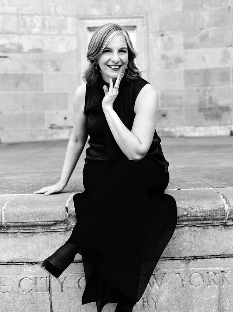 A woman in a black dress sitting on a wall