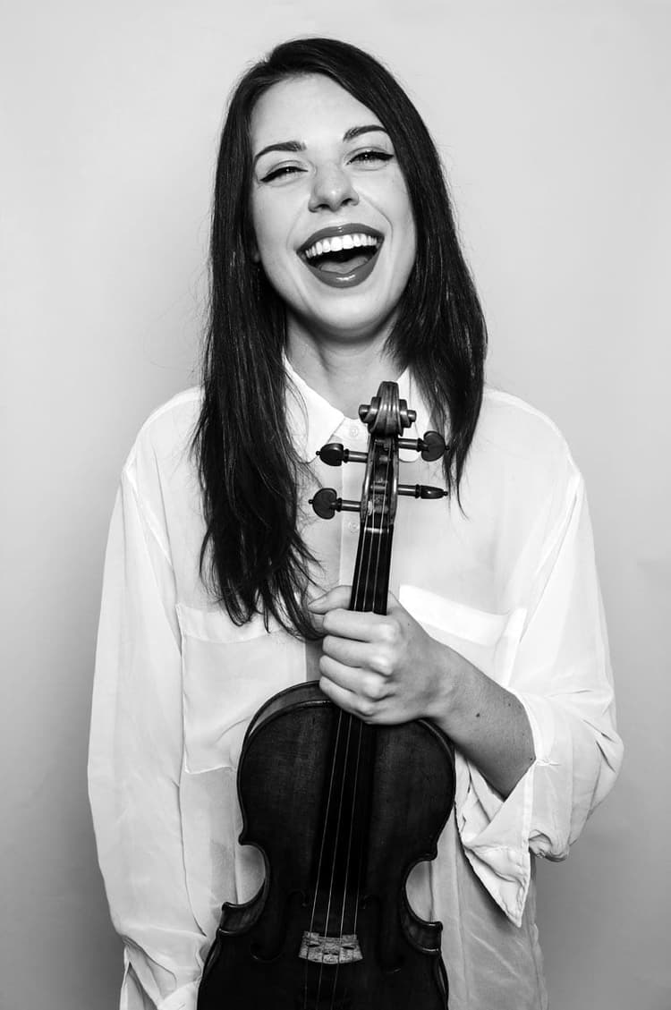 A woman smiling while holding a violin