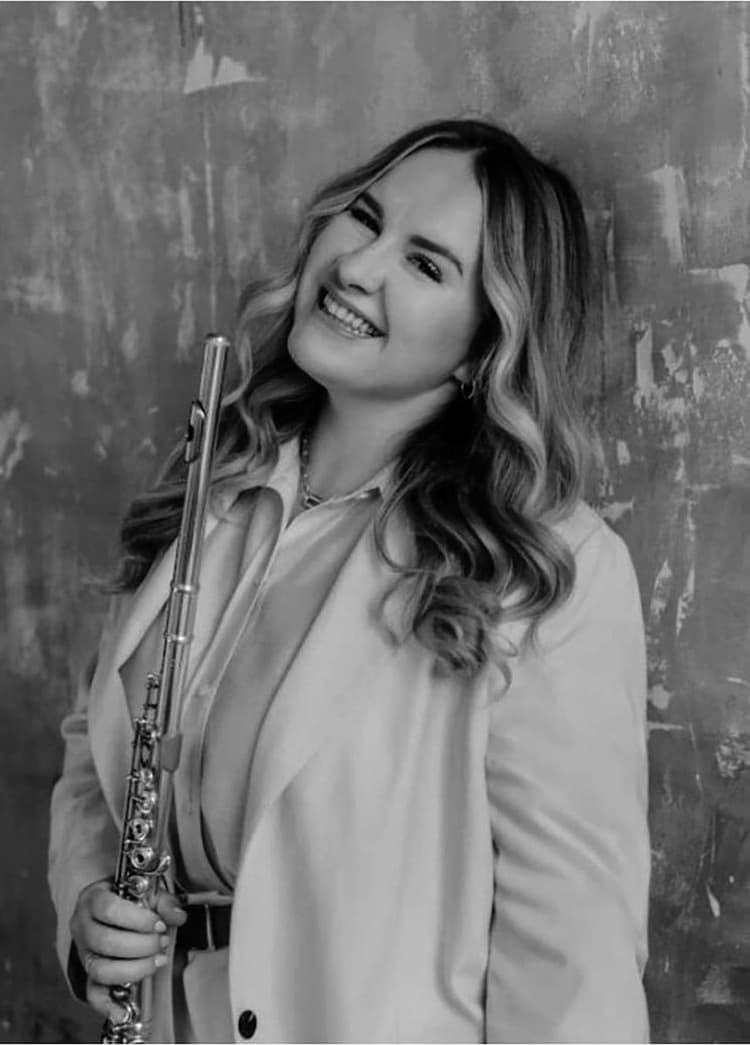 A woman is holding a flute and smiling