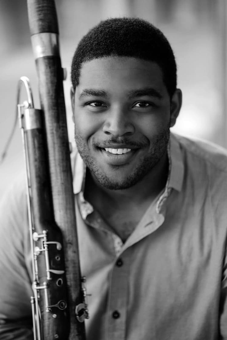 A man is holding a flute and smiling