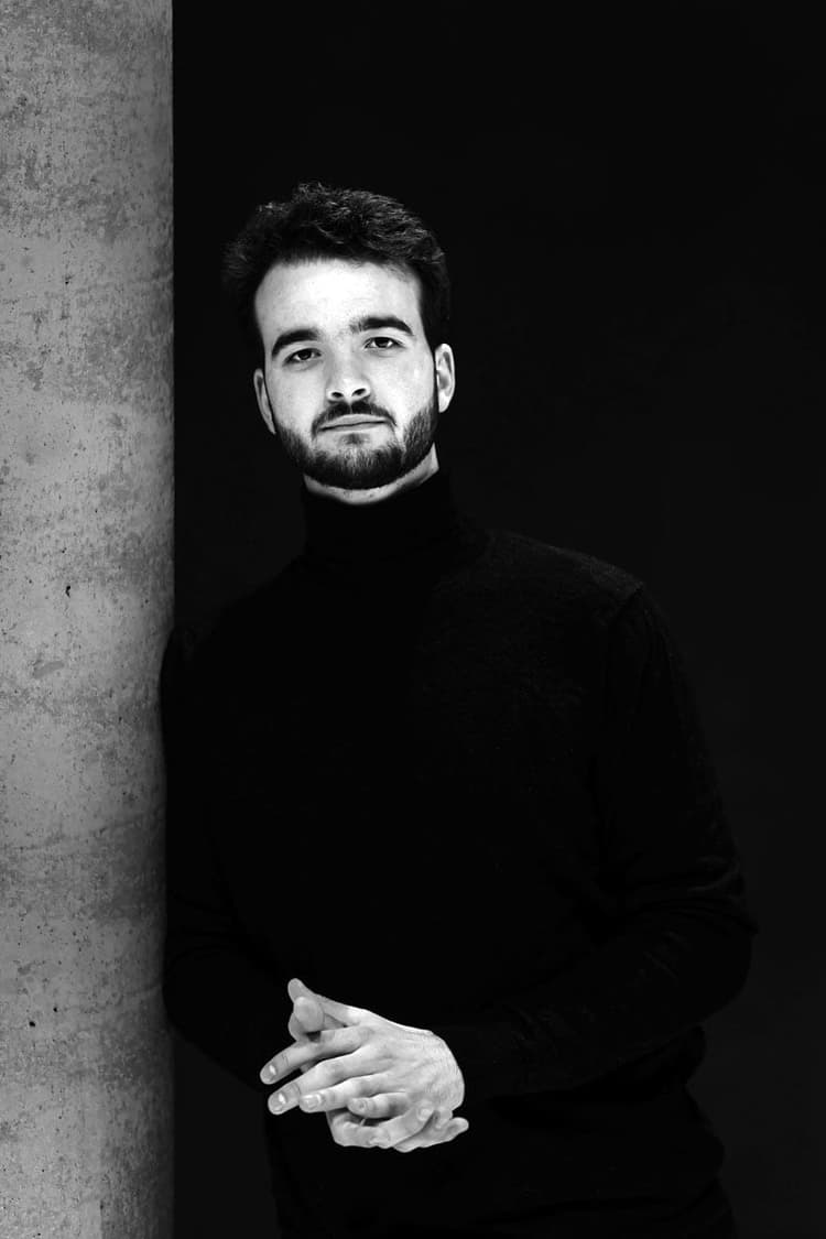 A man standing next to a pillar in a black and white photo
