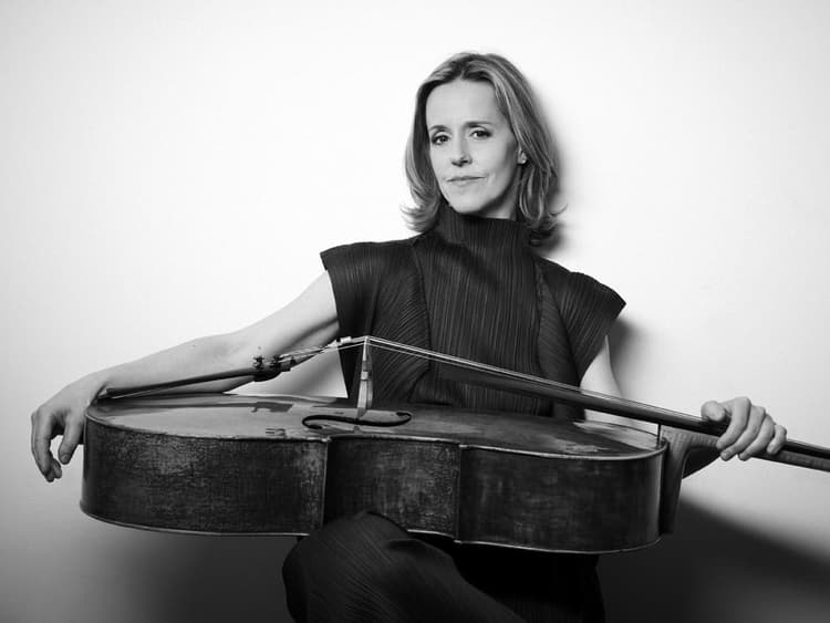 A woman is holding a violin and posing for a picture