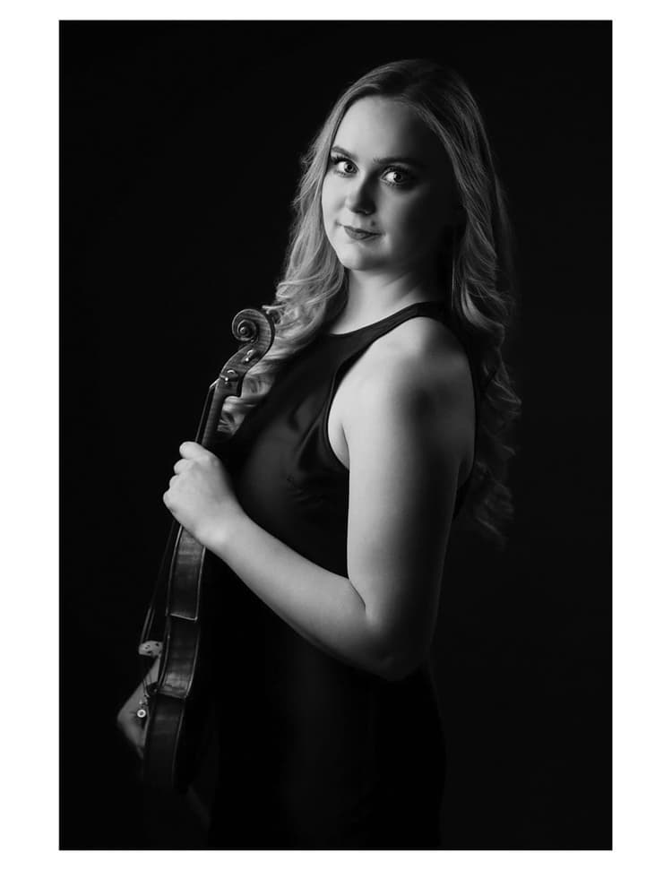 A woman in a black dress holding a violin