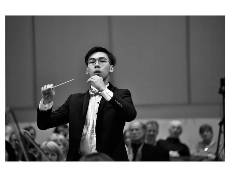 A man in a suit and tie holding a conductor's baton