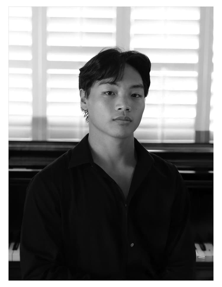 A black and white photo of a man sitting in front of a piano