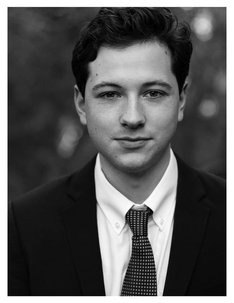 A black and white photo of a man wearing a suit and tie