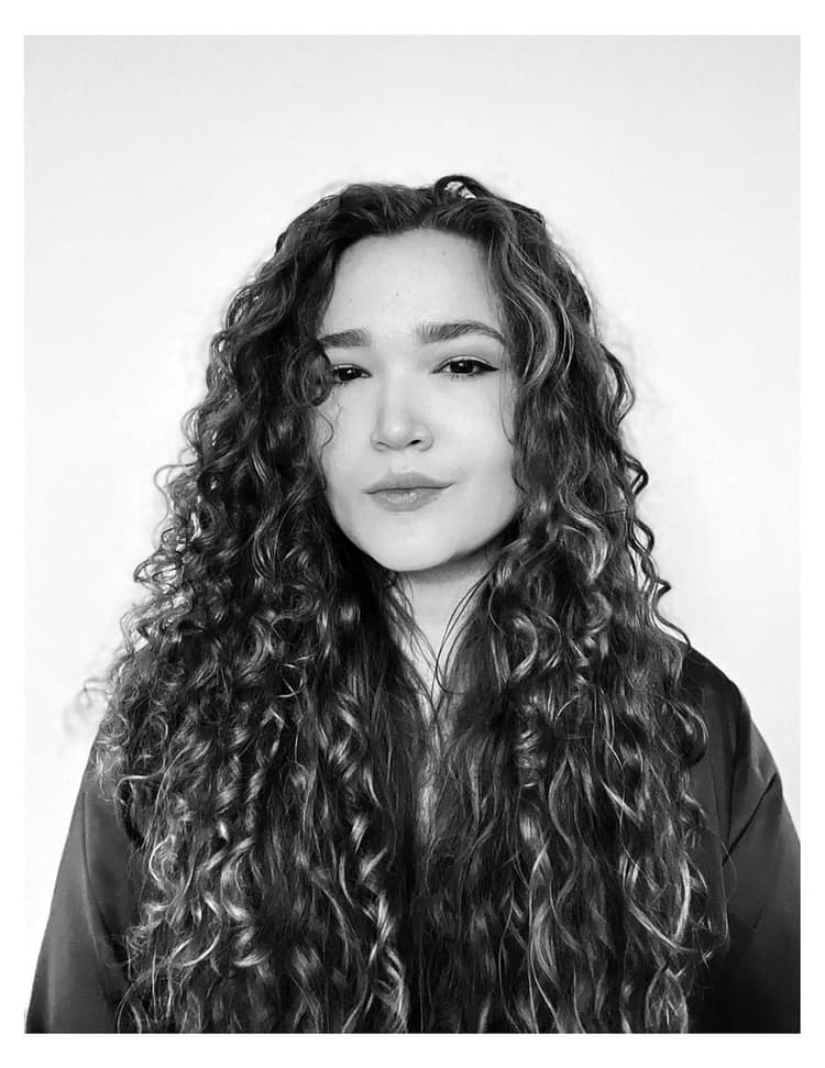 A black and white photo of a woman with long curly hair