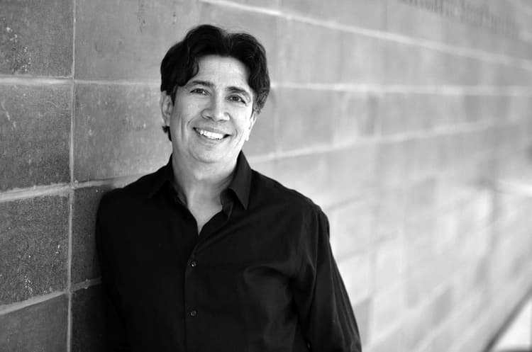 A black and white photo of a man leaning against a wall