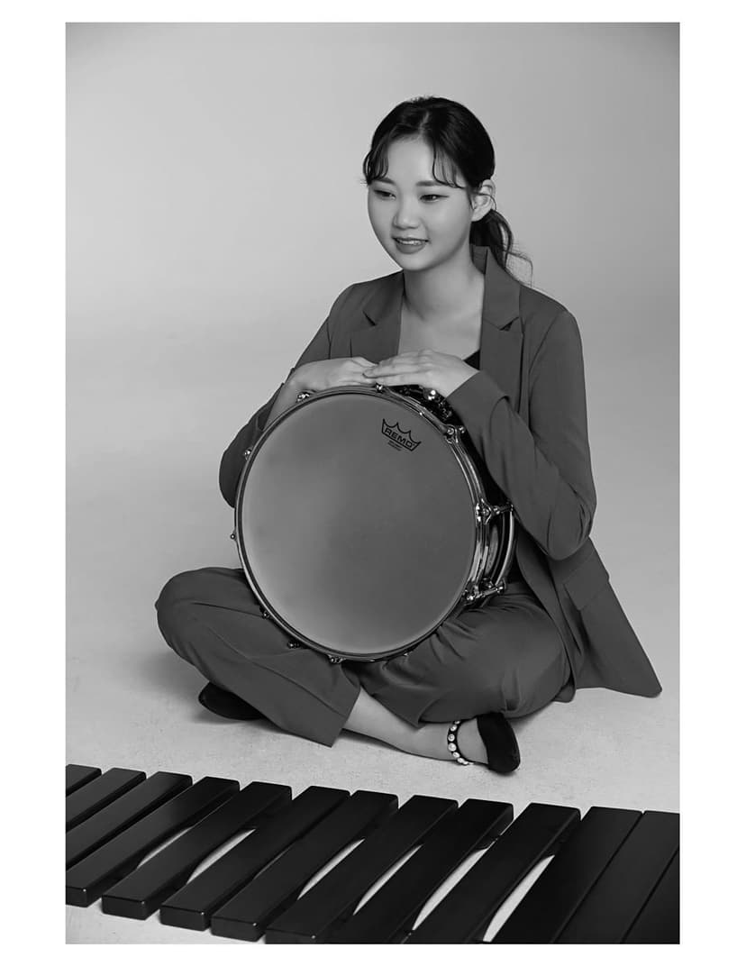A woman sitting on the ground holding a drum