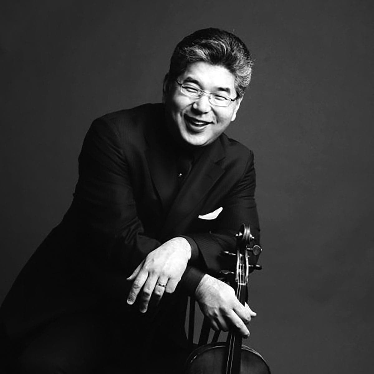 A man in a suit and glasses holding a violin