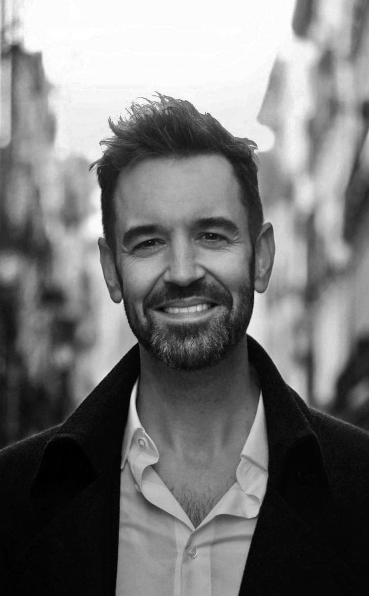 A black and white photo of a man smiling