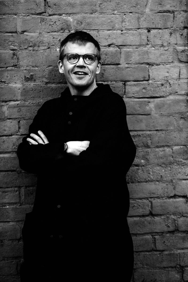 A man standing in front of a brick wall