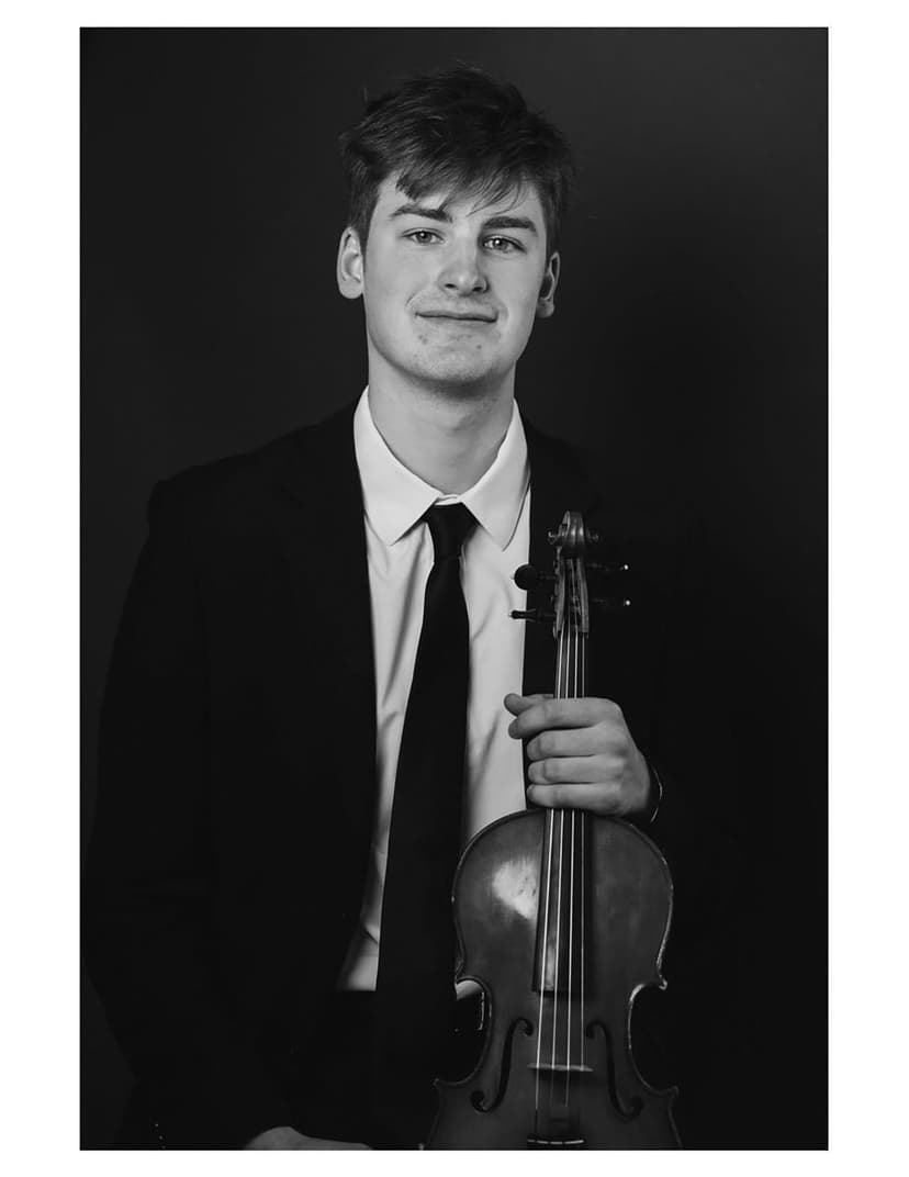 A man in a suit and tie holding a violin