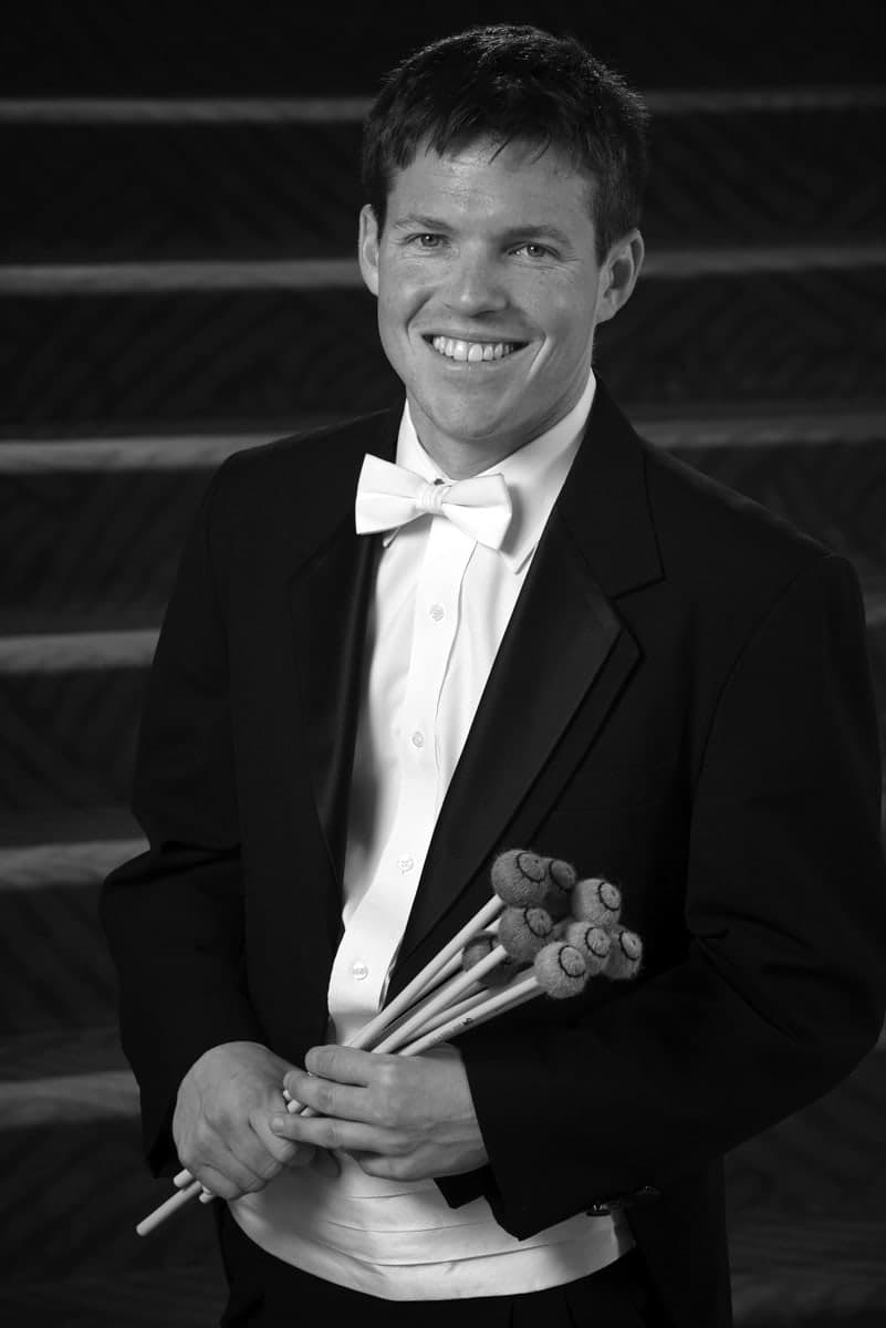 A man in a tuxedo holding a bouquet of flowers