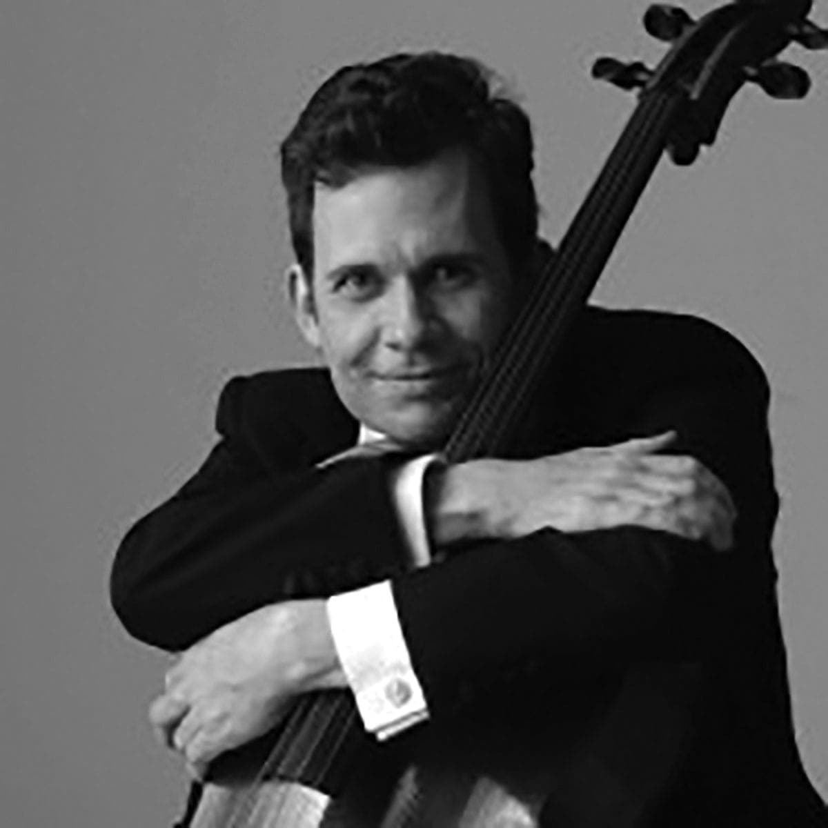 A man in a suit holding a cello