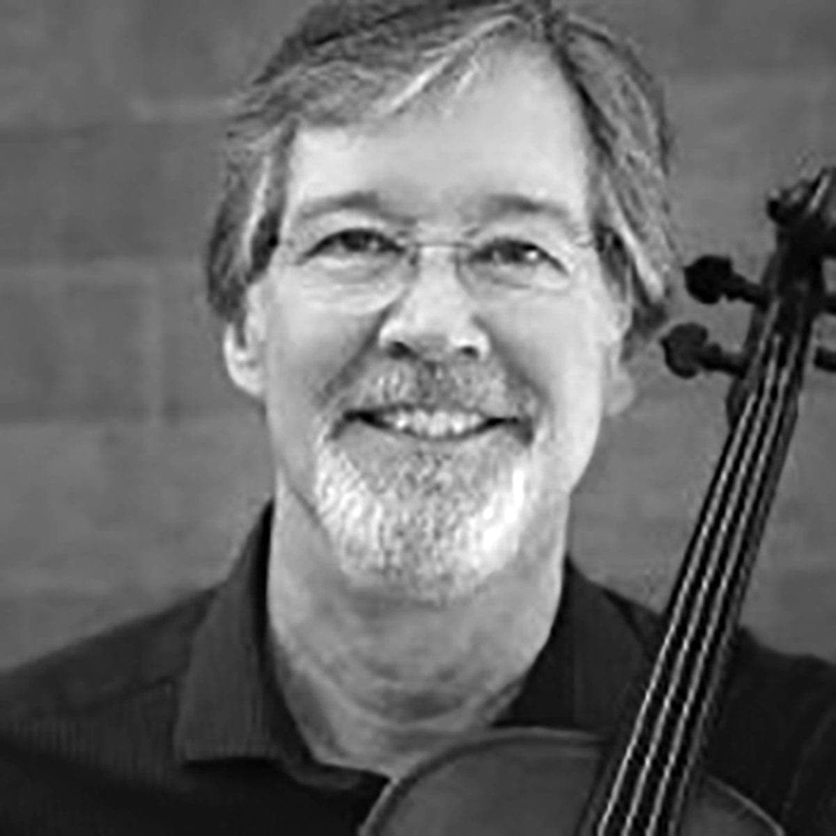 A man holding a violin and smiling at the camera