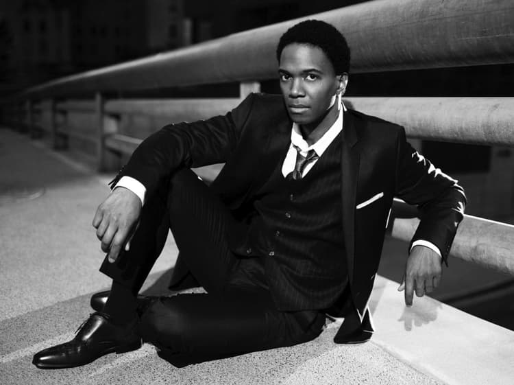 A man in a suit and tie sitting on a ledge