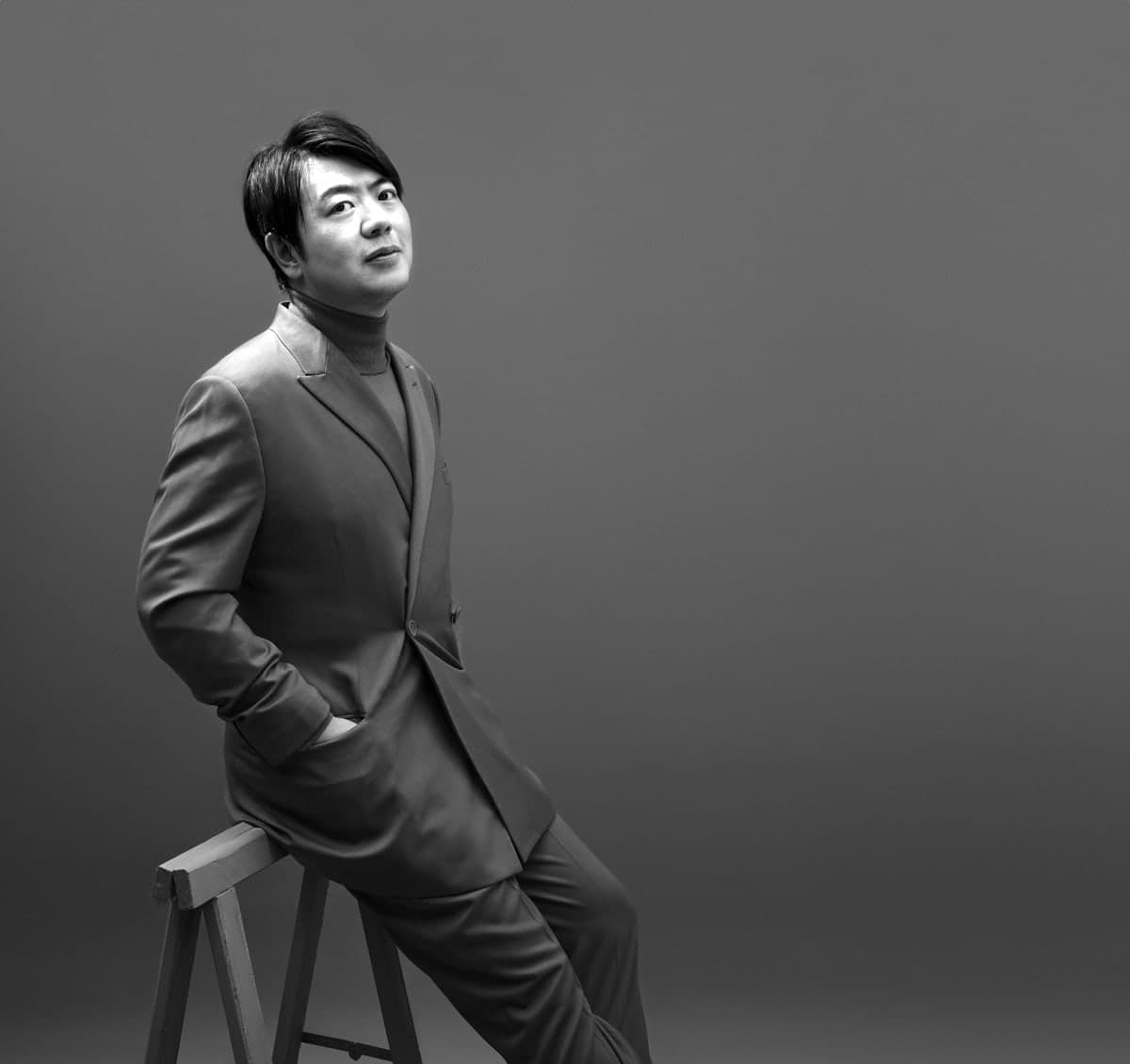 A man in a suit sitting on a stool