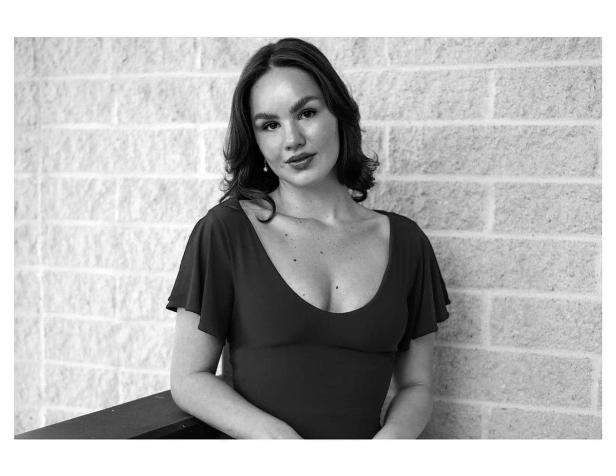 A black and white photo of a woman leaning against a wall