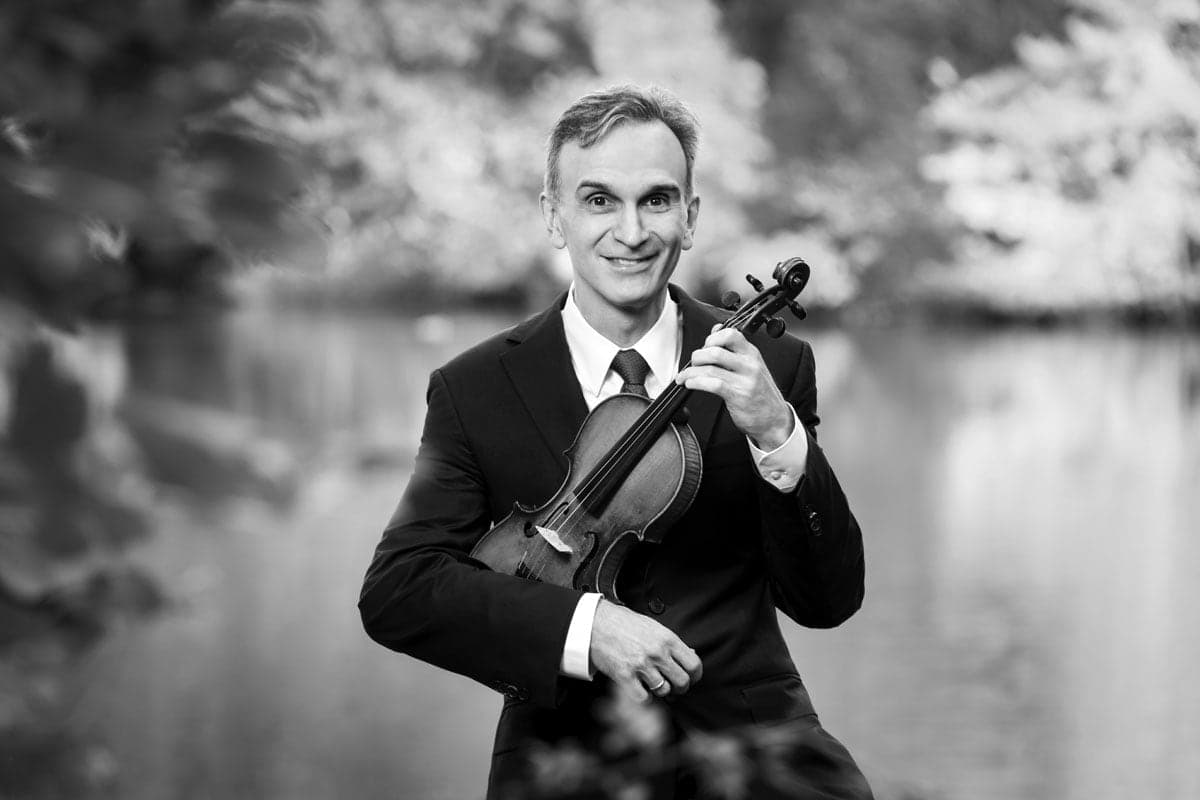 A man in a suit and tie holding a violin