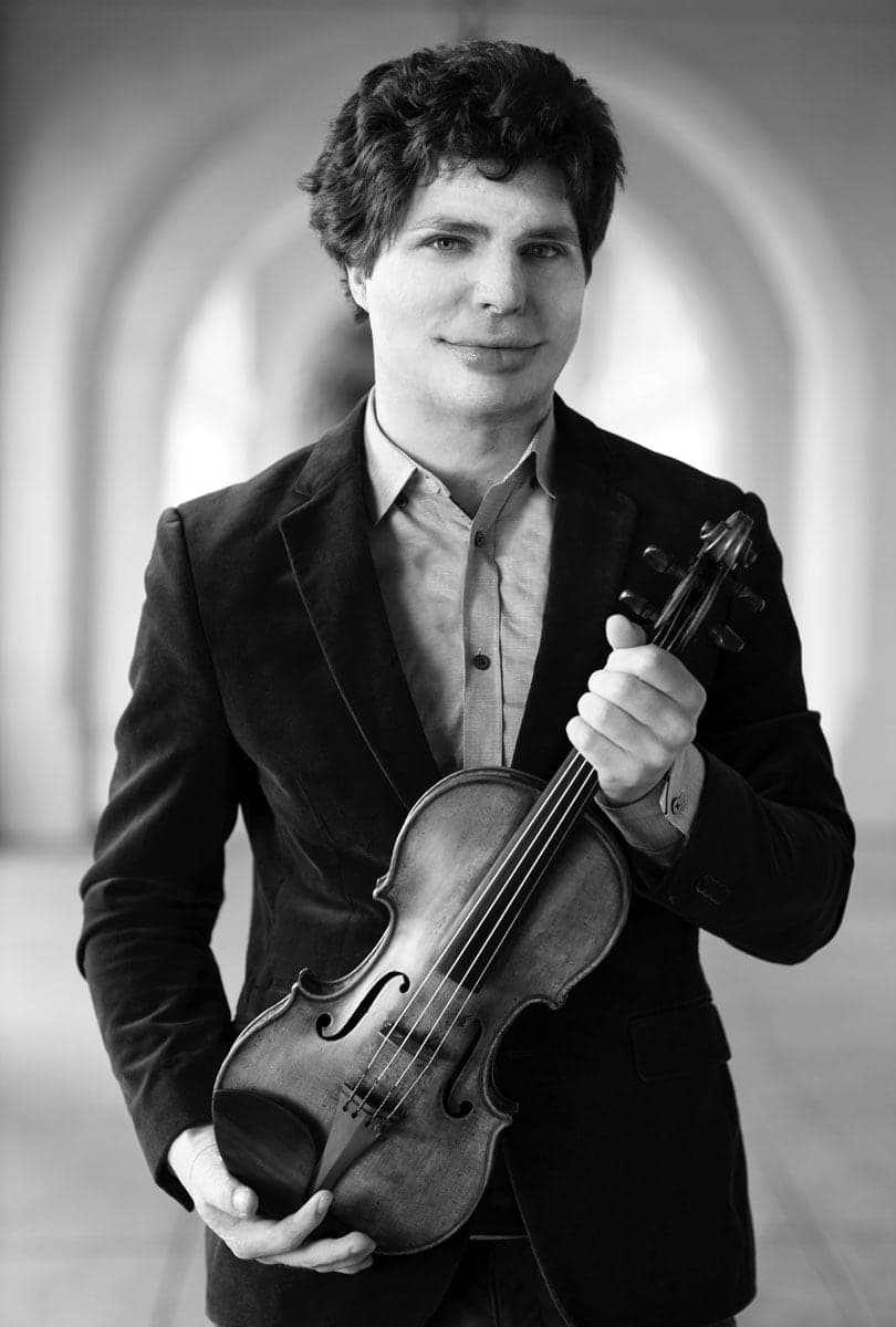 A man in a suit holding a violin