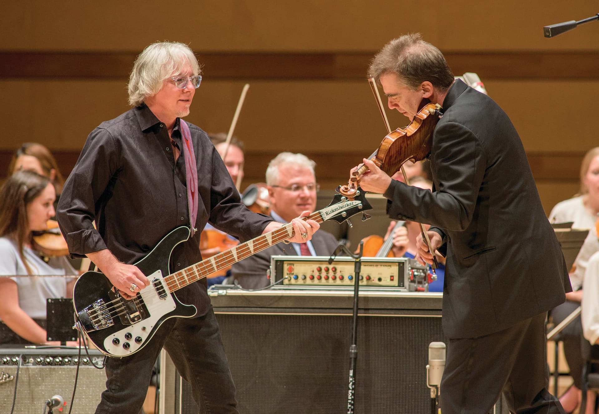 Two men playing instruments in front of an orchestra