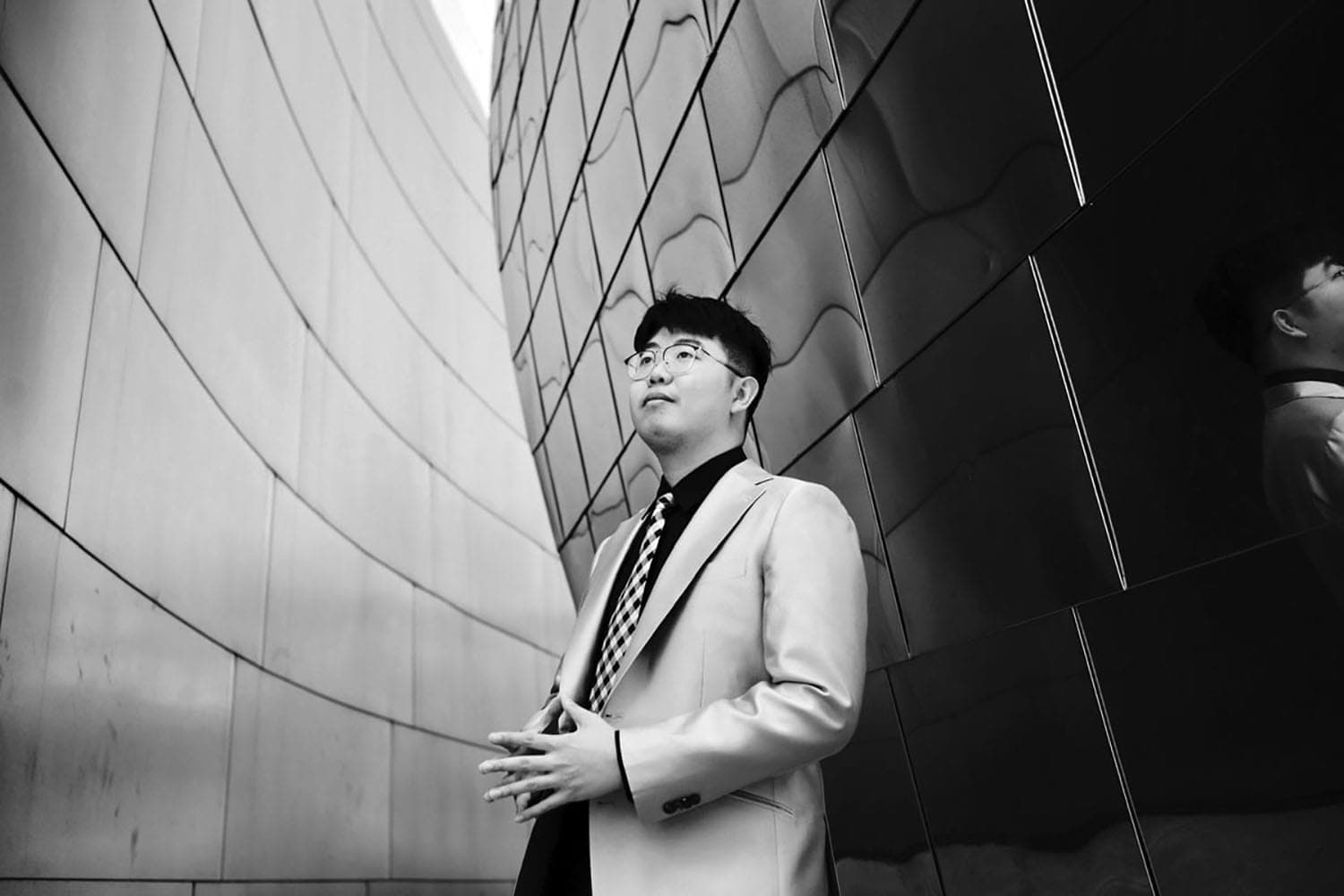 A man in a suit and tie standing in front of a building
