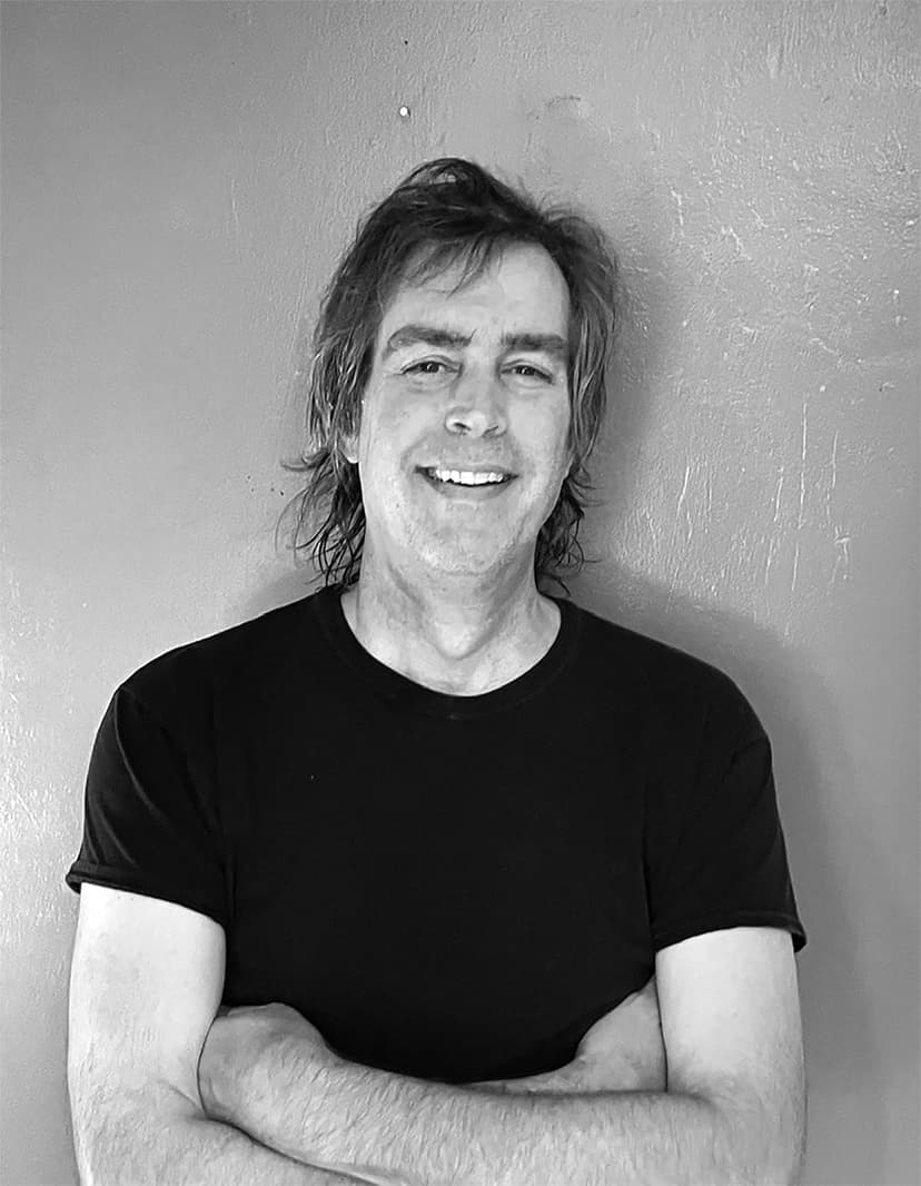 A black and white photo of a man with his arms crossed