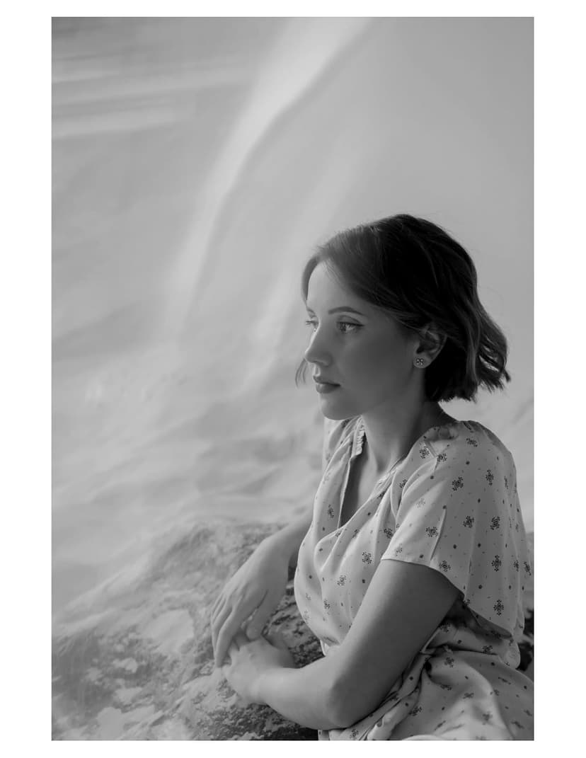 A black and white photo of a woman sitting on a bed