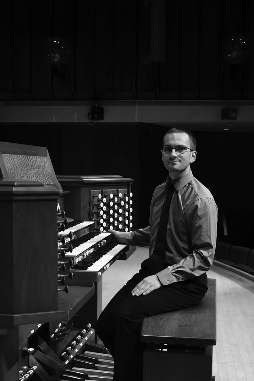 A man sitting on a bench in front of a pipe organ