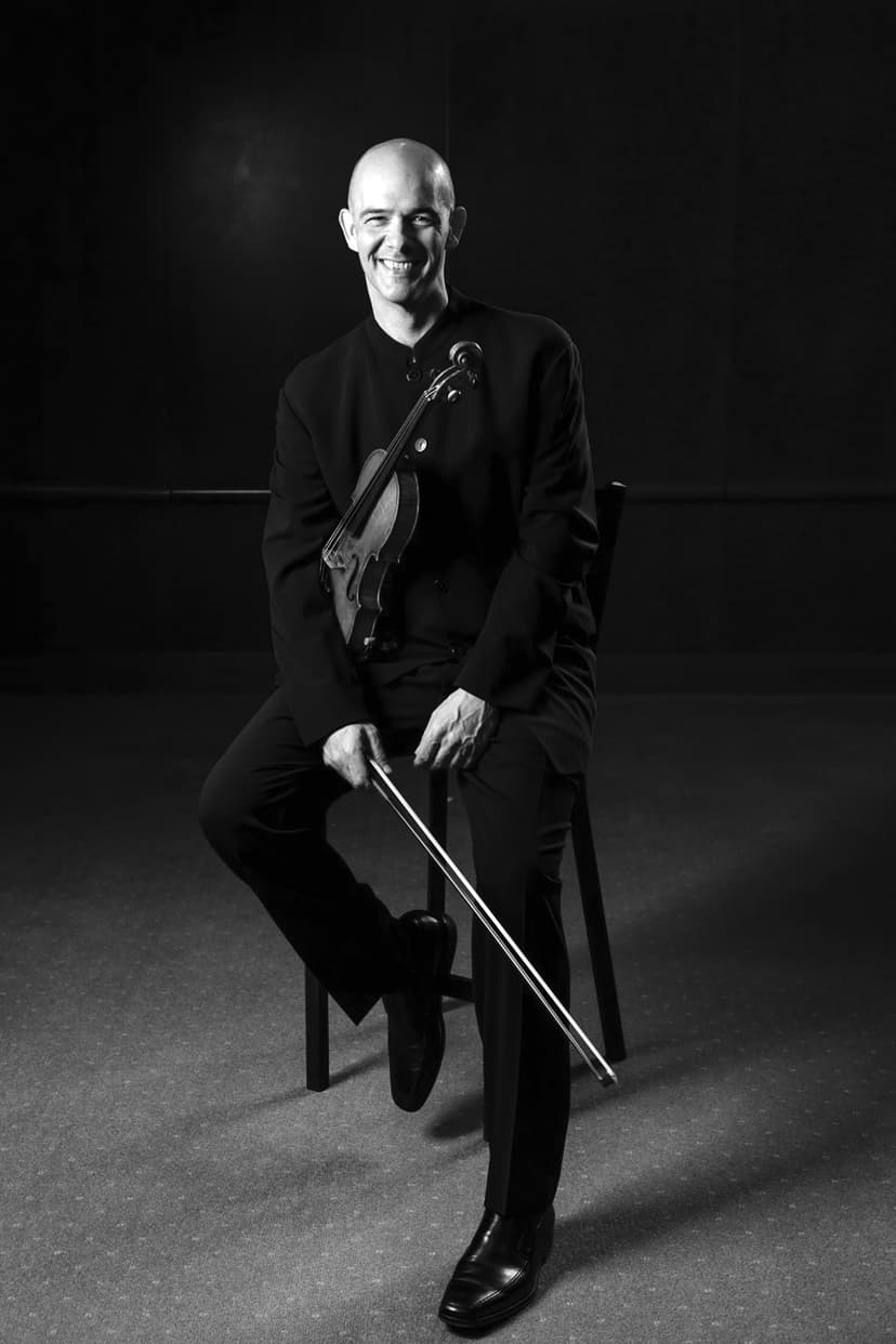 A man sitting on a chair holding a violin