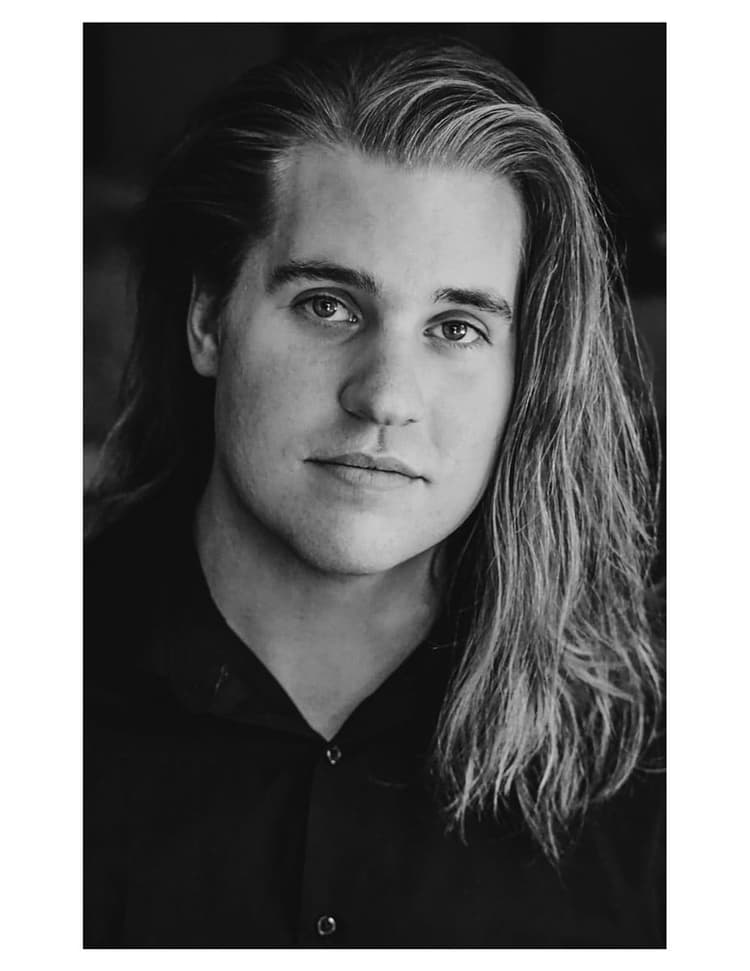 A black and white photo of a man with long hair