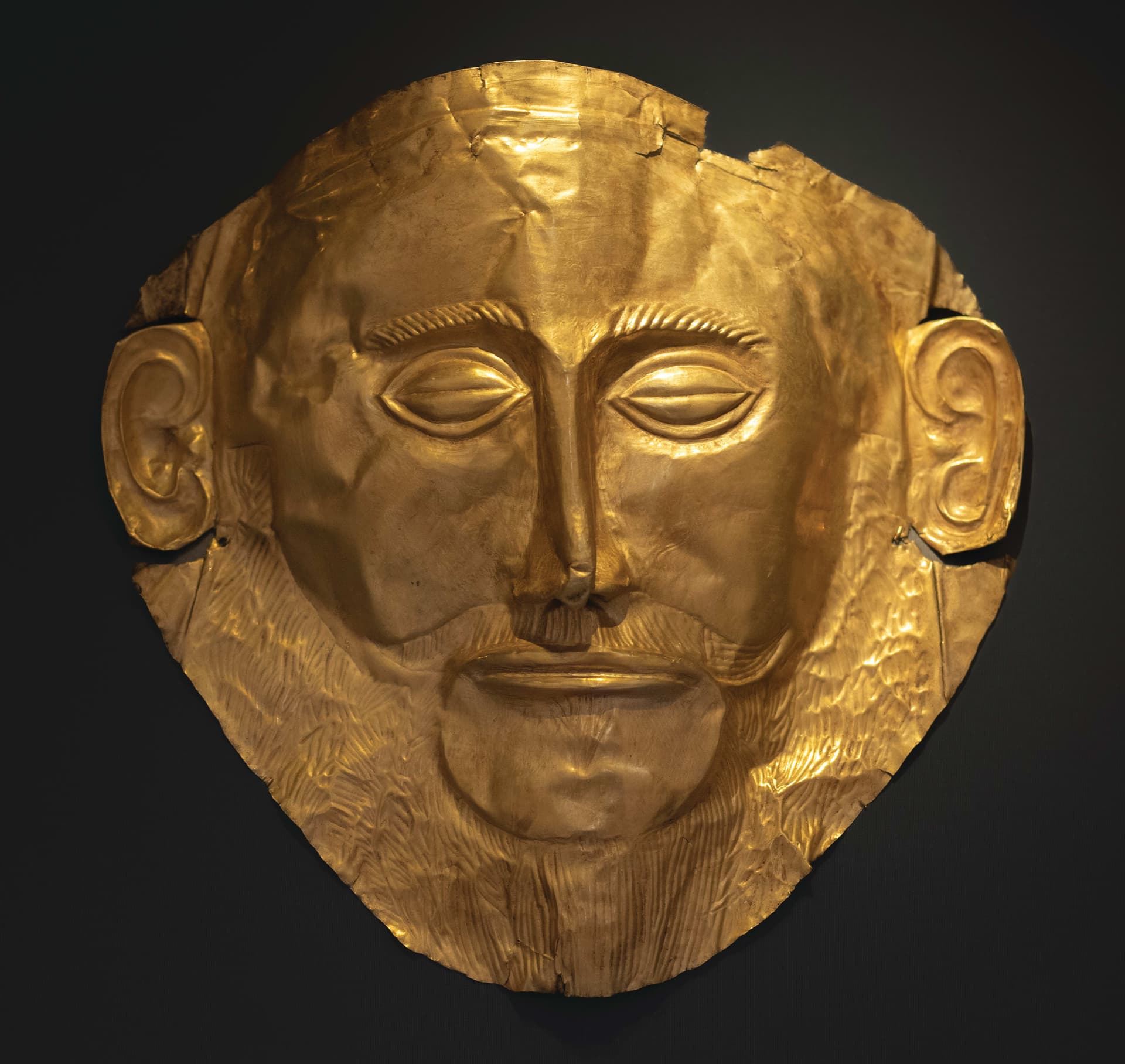 A close up of a gold mask on a black background