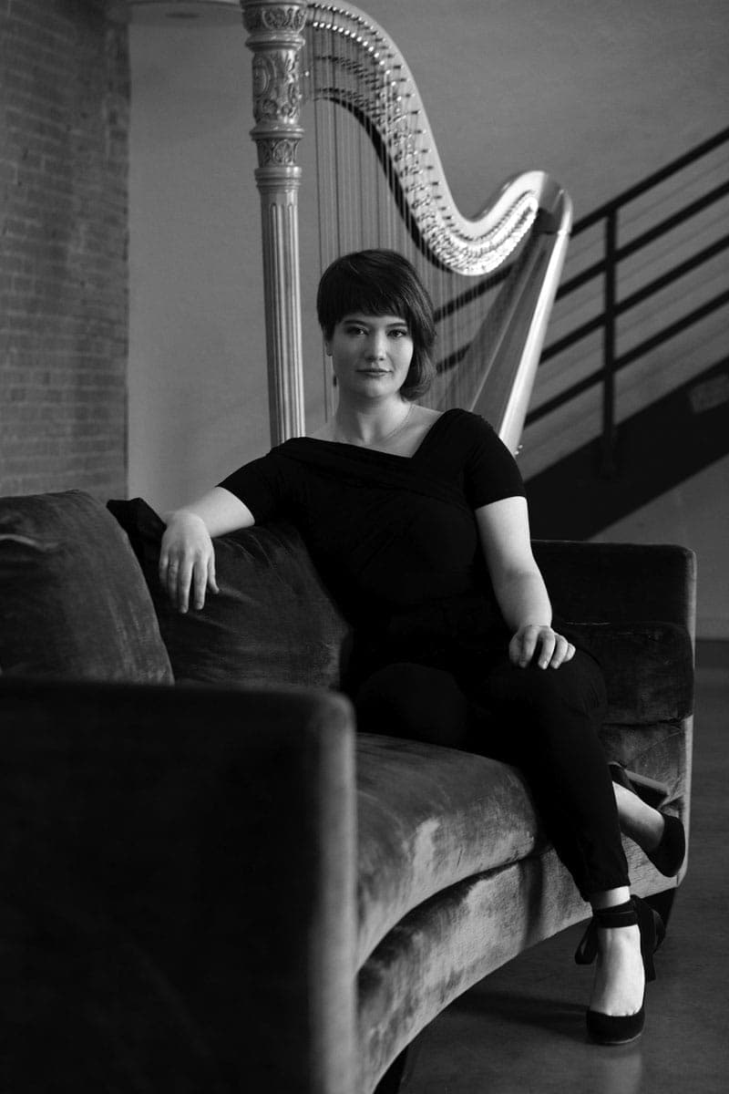 A woman sitting on a couch with a harp