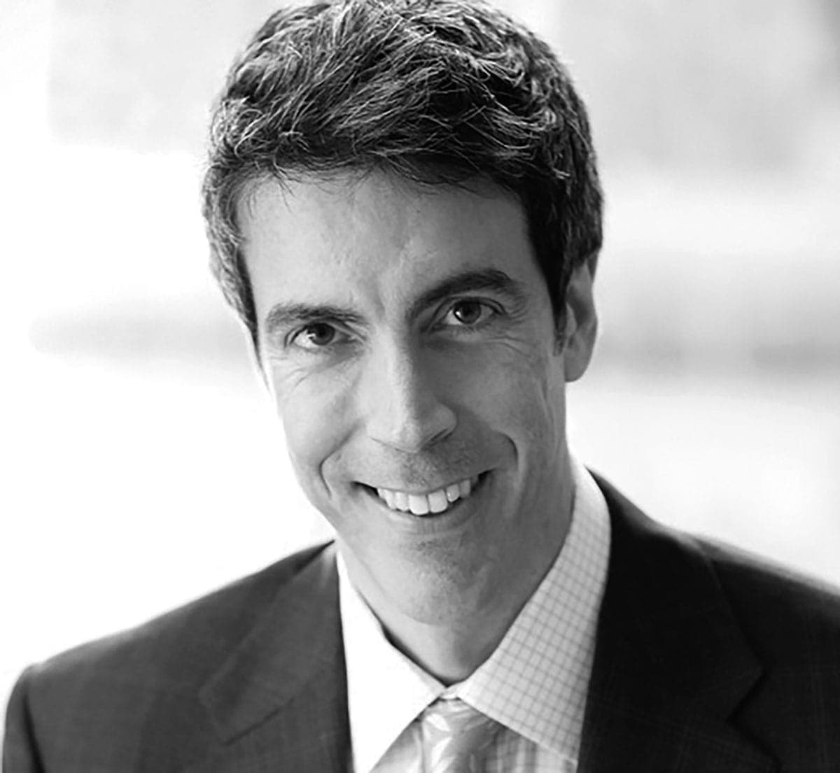 A black and white photo of a man wearing a suit and tie